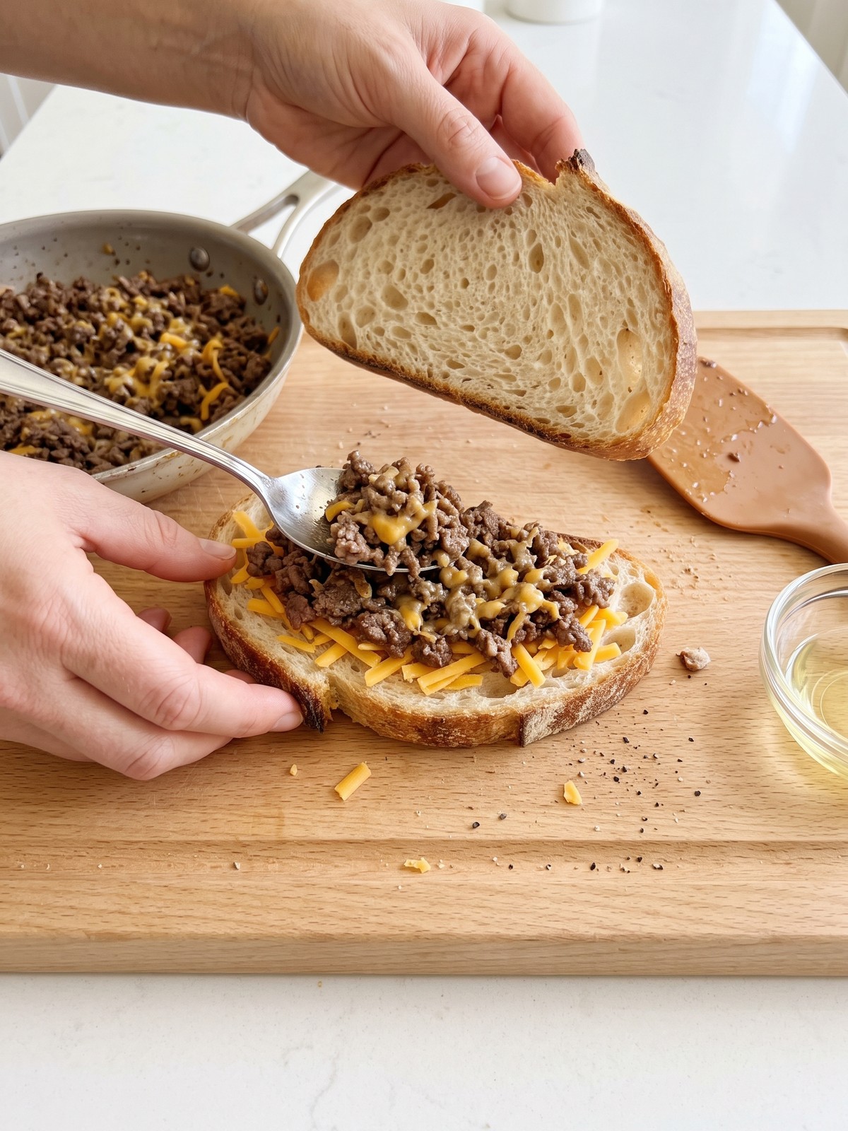 A diagonal cut showing layers of melted cheddar and seasoned ground beef between two slices of toasted sourdough.