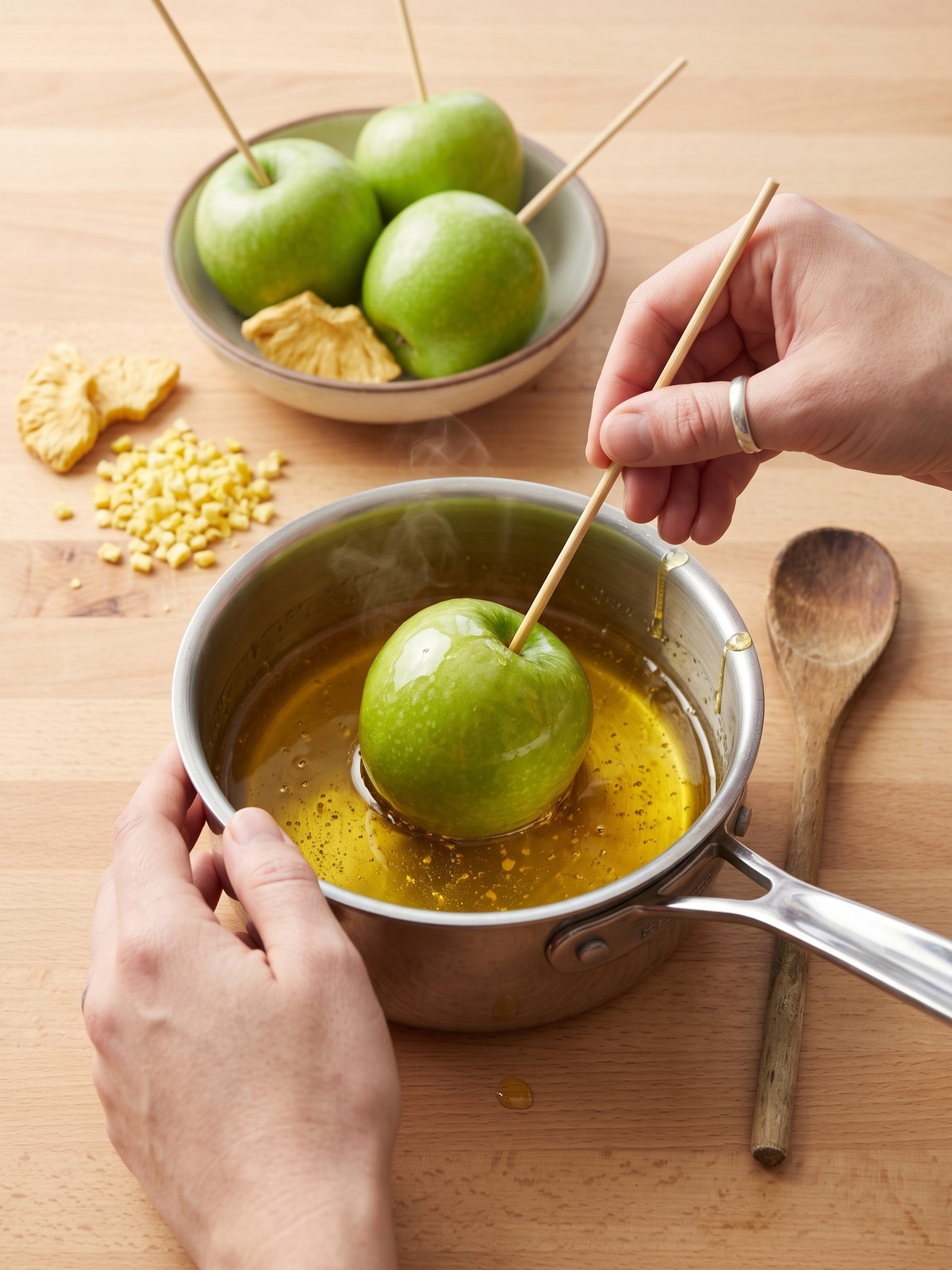 Dipping a Granny Smith apple into glossy yellow candy syrup for Pineapple Lemonade Candy Apples